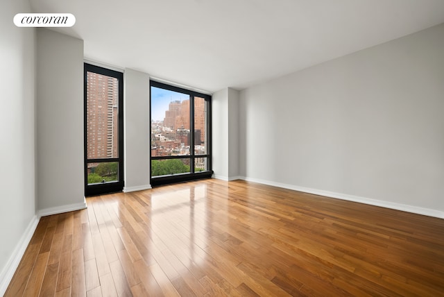 101 Warren St Unit 1720, New York City, NY 10007 - unfurnished room featuring expansive windows, wood finished floors, and a city view
