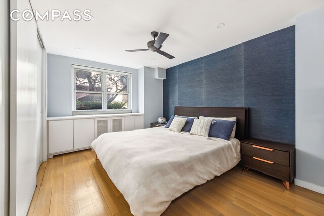 340 E 80th St Unit 1D, New York City, NY 10075 - bedroom with an accent wall, wallpapered walls, light wood-type flooring, and ceiling fan