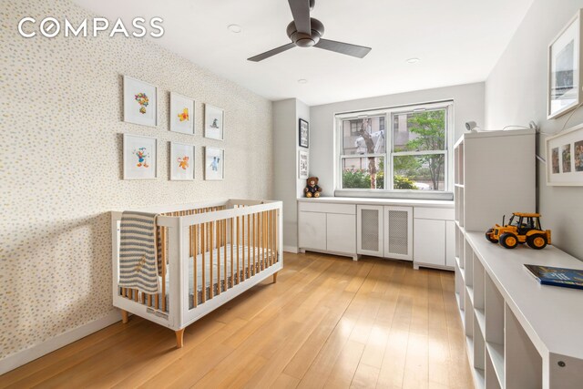 340 E 80th St Unit 1D, New York City, NY 10075 - bedroom with light wood-style flooring, radiator, a crib, wallpapered walls, and a ceiling fan