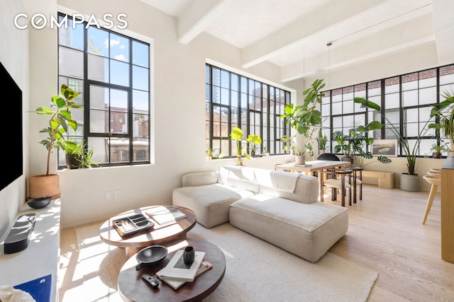 living area featuring beam ceiling, wood finished floors, and a high ceiling