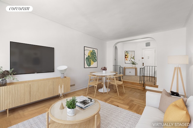 living area featuring arched walkways, baseboards, and visible vents