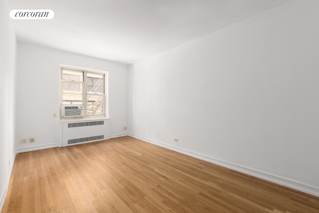 unfurnished room featuring visible vents, radiator, baseboards, cooling unit, and light wood-style flooring