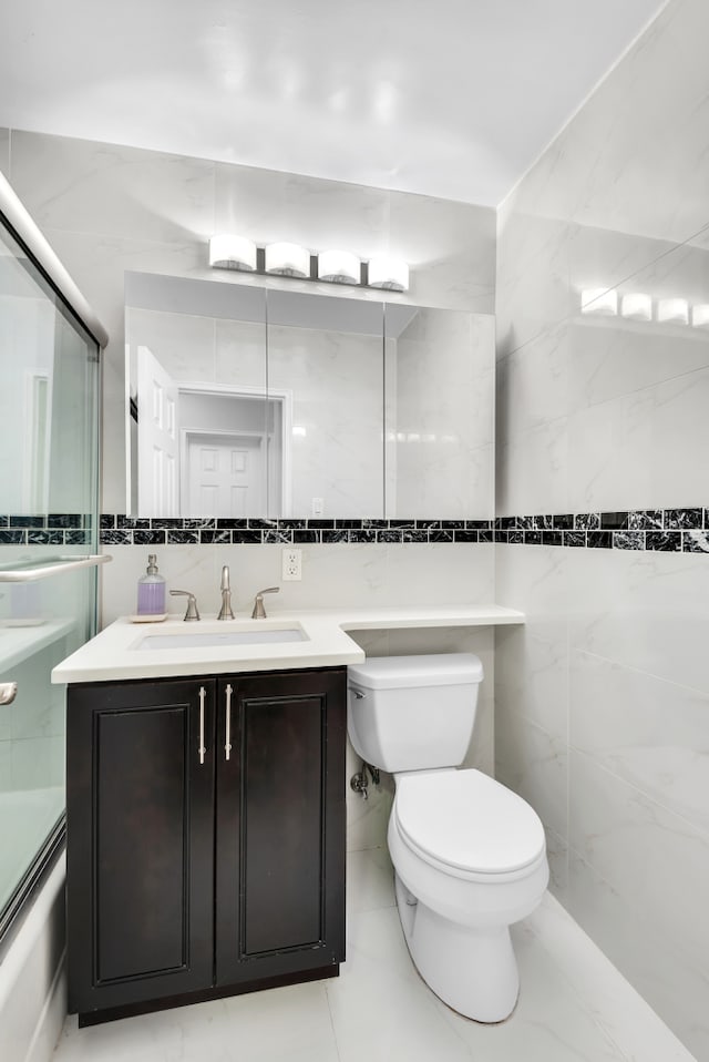 bathroom featuring toilet, tile walls, vanity, shower / bath combination with glass door, and backsplash