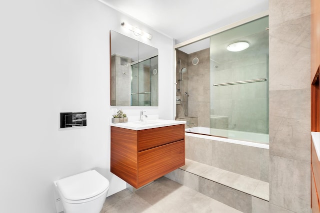 bathroom featuring tile patterned floors, tiled shower / bath, vanity, and toilet