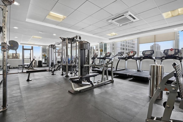 gym featuring a drop ceiling and a healthy amount of sunlight