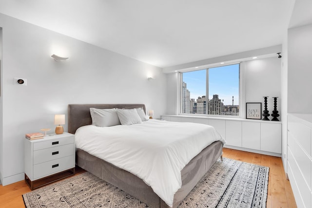 bedroom featuring a view of city and light wood finished floors
