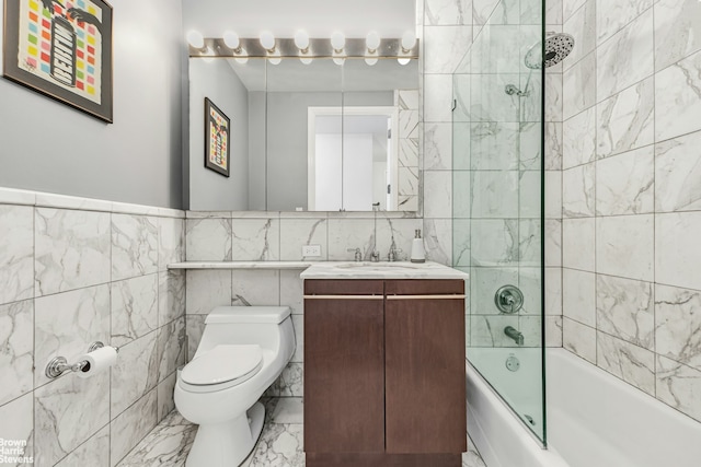 bathroom featuring tile walls, marble finish flooring, bathtub / shower combination, toilet, and vanity