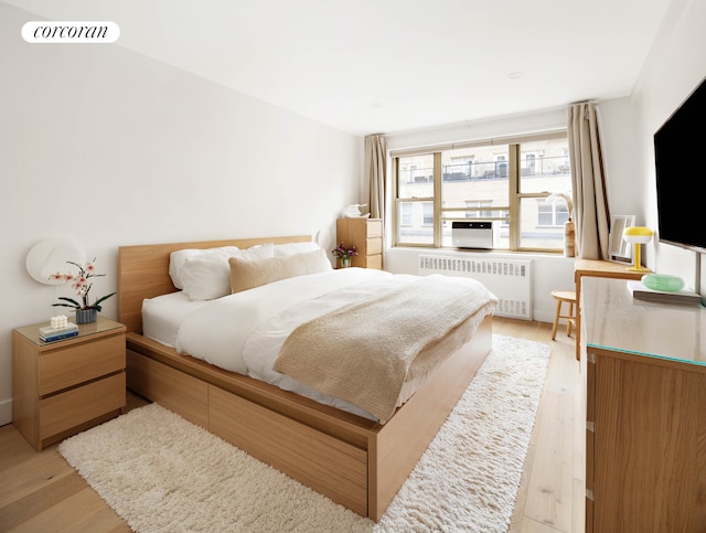 415 E 52nd St Unit 11Fc, New York City, NY 10022 - bedroom featuring radiator heating unit and light wood-type flooring