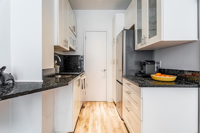 349 W Broadway Unit 9, New York City, NY 10013 - kitchen with white microwave, light wood finished floors, white cabinets, and dark stone countertops