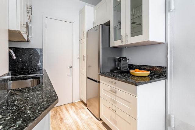 349 W Broadway Unit 9, New York City, NY 10013 - kitchen featuring light wood-style floors, freestanding refrigerator, glass insert cabinets, white cabinets, and dark stone counters