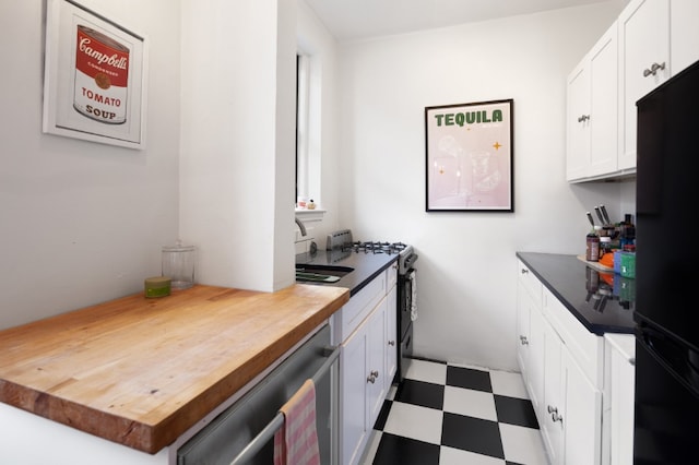 kitchen featuring butcher block counters, stainless steel appliances, white cabinetry, and light floors