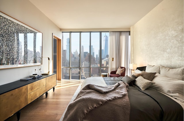 bedroom with a city view, multiple windows, and light wood finished floors