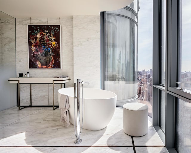 bathroom with a view of city, a freestanding bath, and marble finish floor