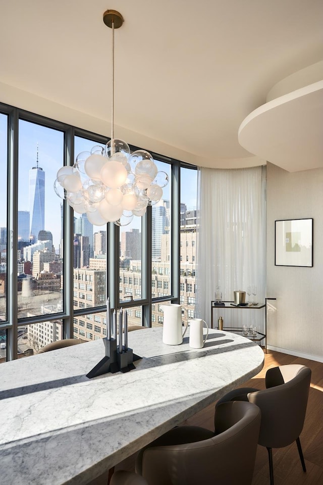 dining space with a view of city, wood finished floors, a healthy amount of sunlight, and baseboards