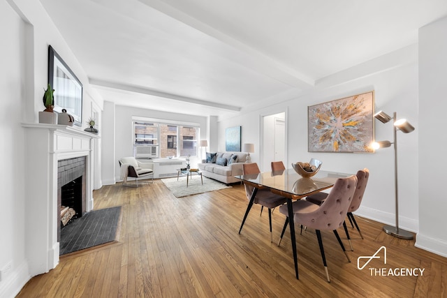424 E 52nd St Unit 5E, New York City, NY 10022 - dining room featuring a fireplace, hardwood / wood-style flooring, beam ceiling, and cooling unit