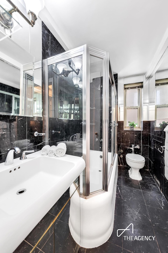 full bath featuring tile walls, toilet, and shower / bath combination with glass door
