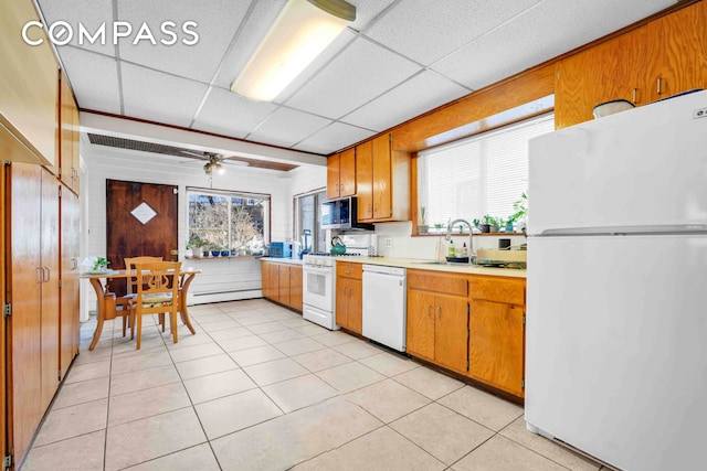 kitchen with white appliances, a sink, a drop ceiling, light countertops, and light tile patterned flooring