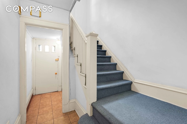 staircase featuring tile patterned floors and baseboards