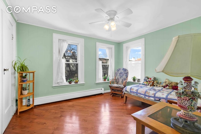 bedroom with ornamental molding, hardwood / wood-style floors, a baseboard radiator, and a ceiling fan
