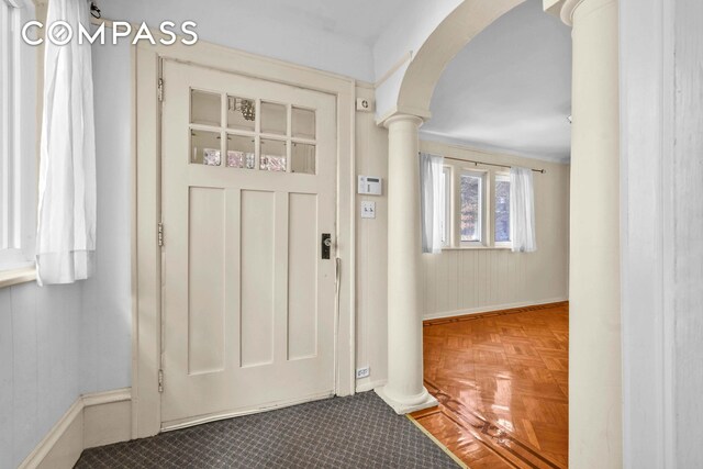 entrance foyer featuring ornate columns, baseboards, and arched walkways