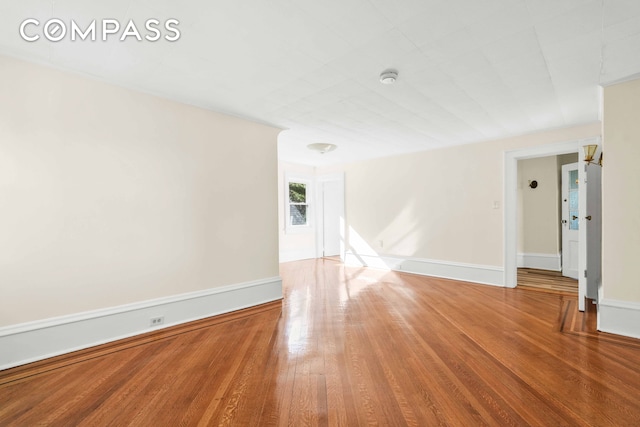 spare room with wood finished floors, a smoke detector, and baseboards
