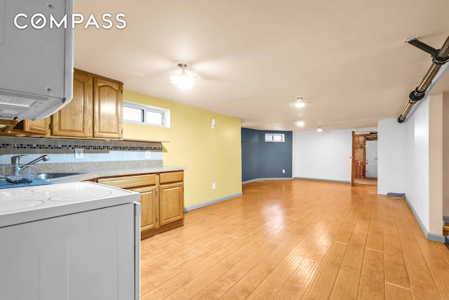 kitchen featuring white range with electric stovetop, light countertops, a sink, light wood-style flooring, and baseboards