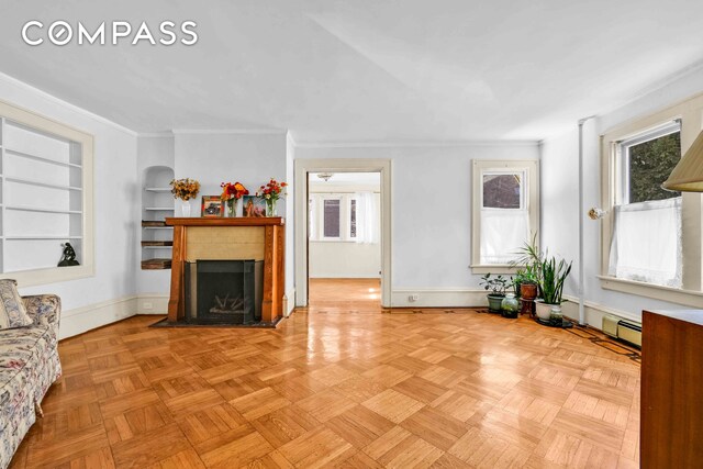 living room with built in features, a fireplace with flush hearth, a baseboard heating unit, ornamental molding, and baseboards