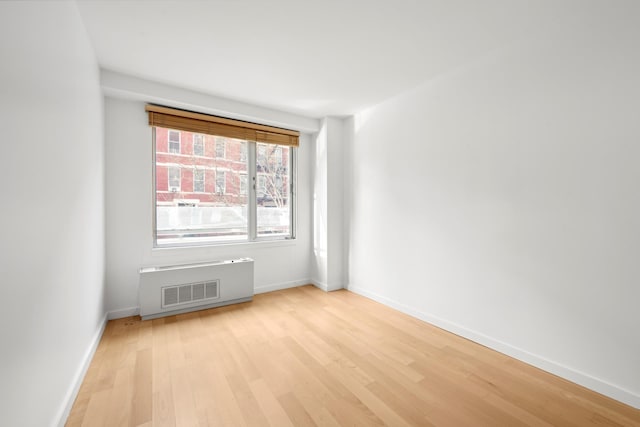 spare room with baseboards, visible vents, and light wood finished floors