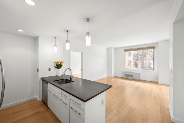 kitchen with a sink, stainless steel appliances, light wood-type flooring, a peninsula, and dark countertops