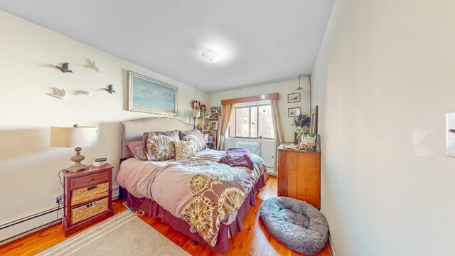 bedroom featuring a baseboard radiator and wood finished floors