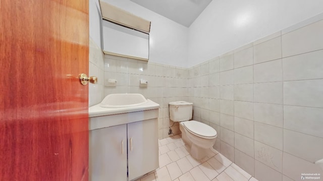 bathroom featuring toilet, tile walls, tile patterned flooring, and vanity