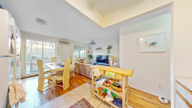 dining room with an AC wall unit and light wood-style floors
