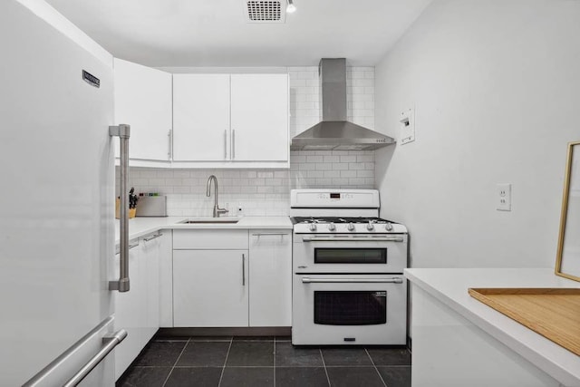 kitchen with visible vents, white appliances, wall chimney range hood, white cabinets, and a sink