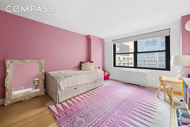 225 E 57th St Unit 14E, New York City, NY 10022 - bedroom featuring wood finished floors, radiator, and baseboards