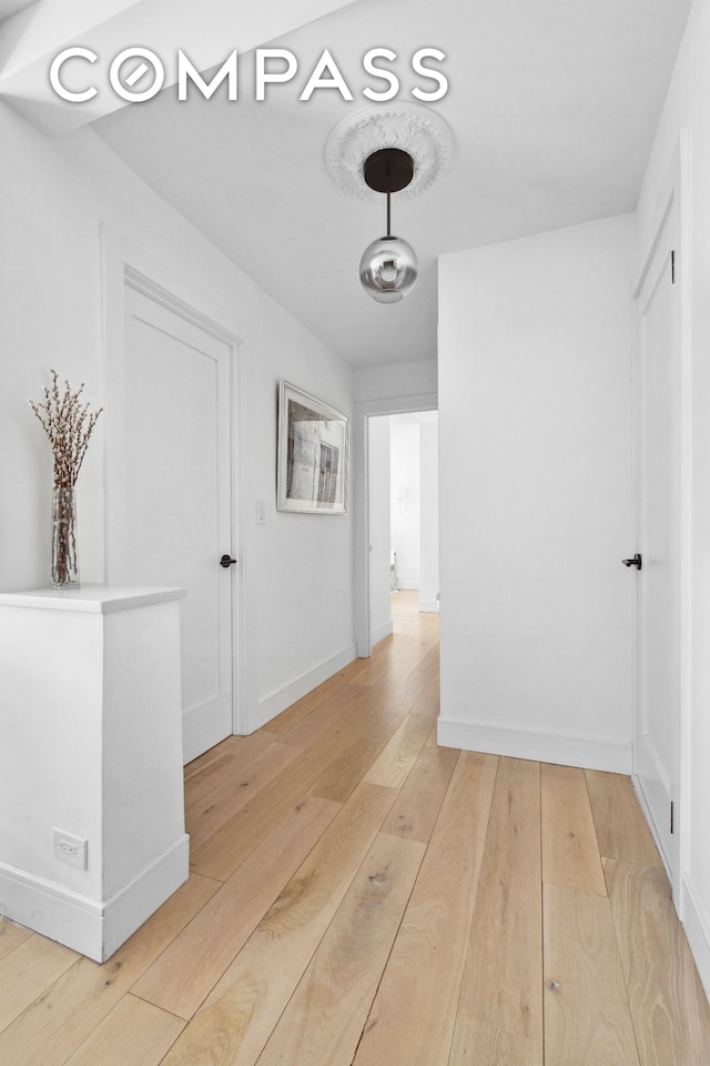 hallway featuring baseboards and light wood-style flooring