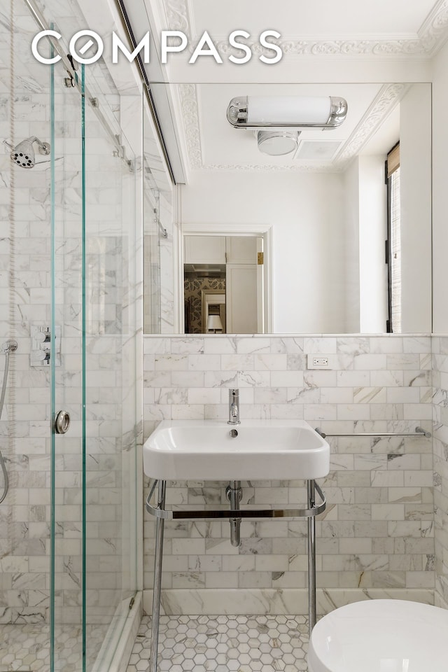 bathroom with a stall shower, tile walls, toilet, tile patterned flooring, and a sink