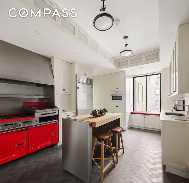 kitchen featuring built in refrigerator, light countertops, a sink, oven, and a kitchen island