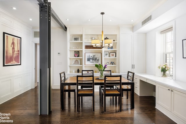 dining space with a chandelier, dark wood-style flooring, a decorative wall, built in features, and ornamental molding