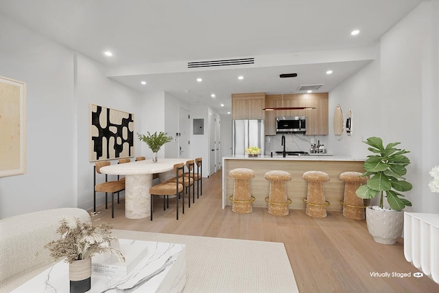 interior space featuring appliances with stainless steel finishes, modern cabinets, tasteful backsplash, light wood finished floors, and recessed lighting