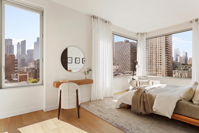 611 W 56th St Unit 12, New York City, NY 10019 - bedroom with a skyline view, wood finished floors, and baseboards