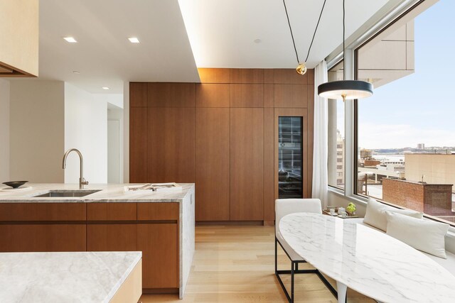 611 W 56th St Unit 12, New York City, NY 10019 - kitchen featuring a sink, brown cabinetry, light wood-type flooring, and modern cabinets