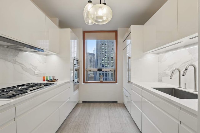 kitchen featuring light countertops, backsplash, white cabinets, appliances with stainless steel finishes, and a sink