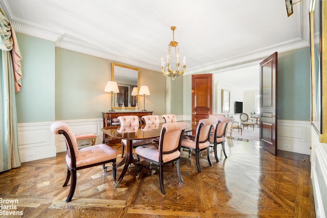 dining area featuring a chandelier, a wainscoted wall, crown molding, and a decorative wall
