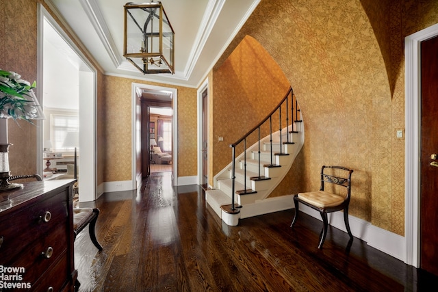 foyer entrance with wallpapered walls, dark wood-style floors, ornamental molding, stairs, and plenty of natural light