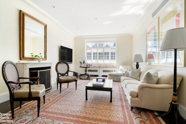living area with crown molding, wood finished floors, a fireplace, and baseboards
