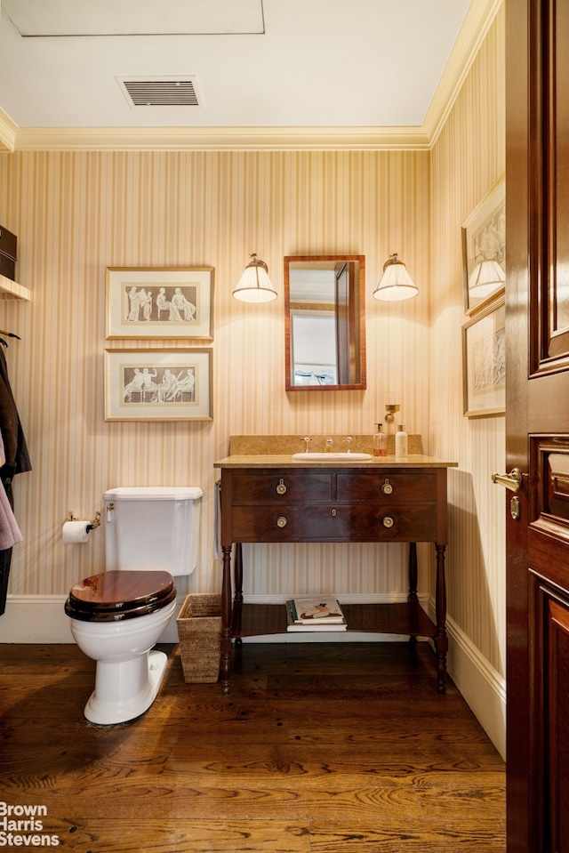 half bath with toilet, wallpapered walls, baseboards, wood finished floors, and vanity