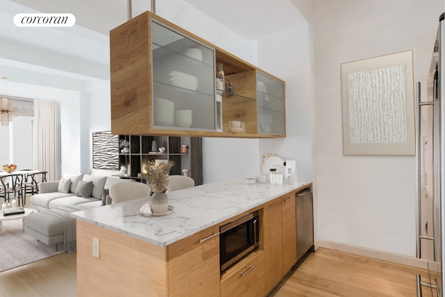 kitchen featuring stainless steel microwave, light wood finished floors, light stone counters, and modern cabinets