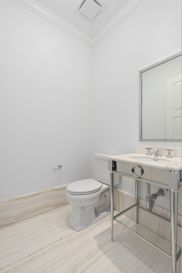 half bathroom with toilet, ornamental molding, and a sink