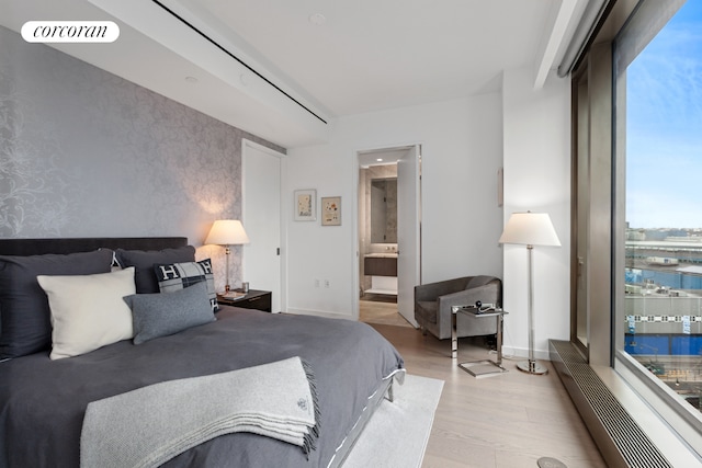 500 W 18th St Unit W9D, New York City, NY 10011 - bedroom featuring visible vents, baseboards, wallpapered walls, wood finished floors, and connected bathroom