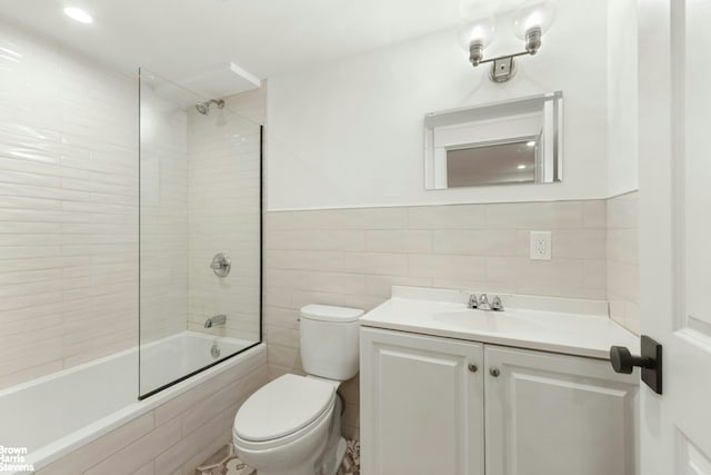full bathroom featuring toilet, tile walls, vanity, and tiled shower / bath